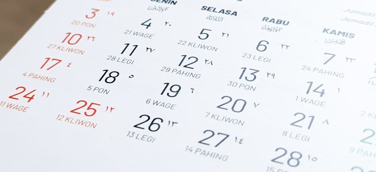 Blurred view and selective focus of Javanese Indonesian calender page of holiday date of the month exposed by side lighting.